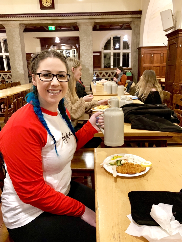 Personne avec une chope de bière à une table commune à l'intérieur d'un restaurant.