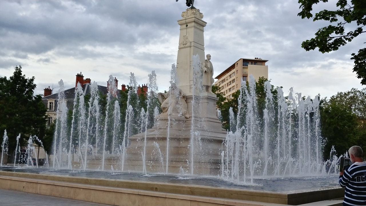Fontaine avec statues sur une place de ville.