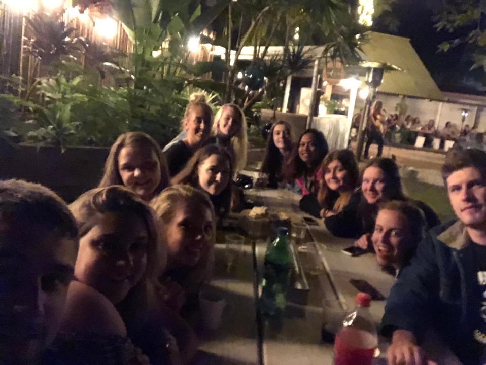 Groupe de personnes rassemblées autour d'une longue table la nuit.