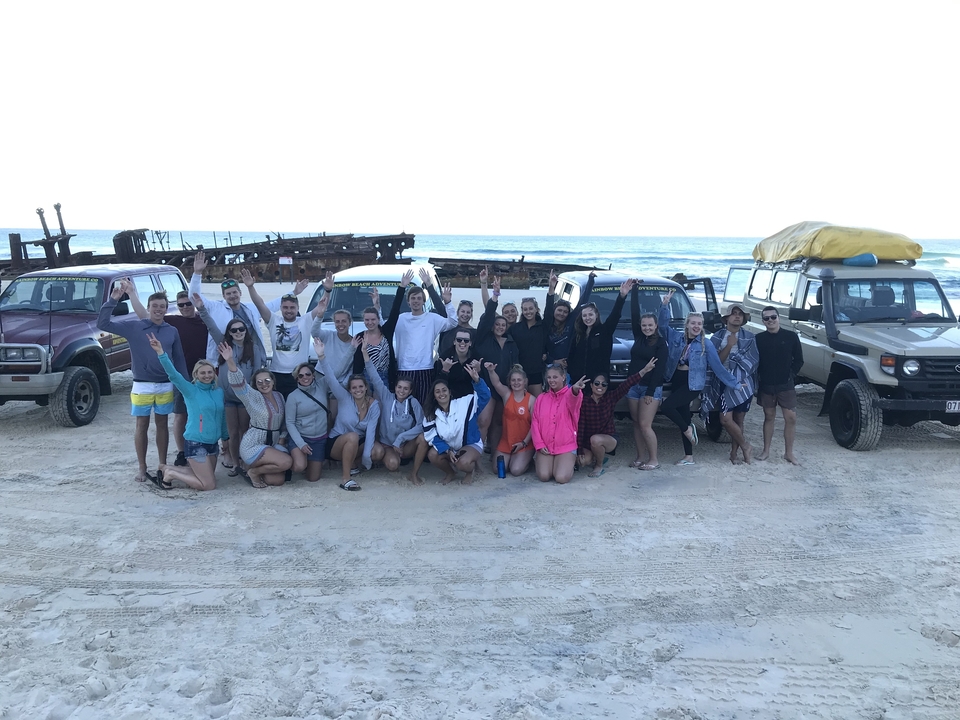 Grand groupe posant avec des véhicules 4x4 sur une plage.