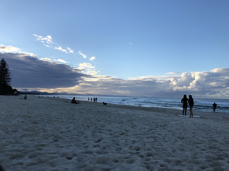 Plage de sable avec des gens et un ciel dramatique.