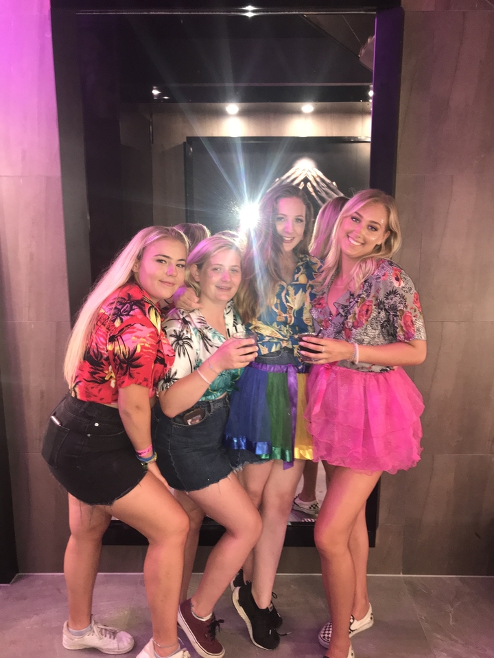 Groupe de personnes à l'intérieur d'un club avec des tenues colorées.