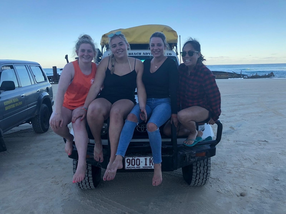 Des gens assis sur une jeep sur une plage de sable.