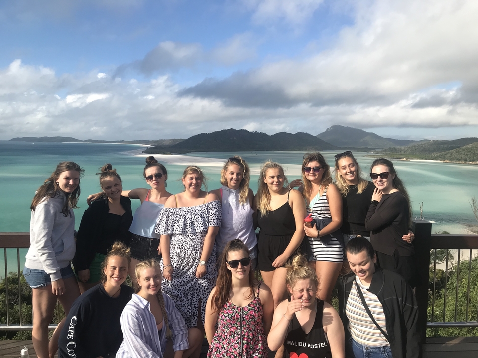 Groupe de personnes posant devant l'océan et les montagnes.