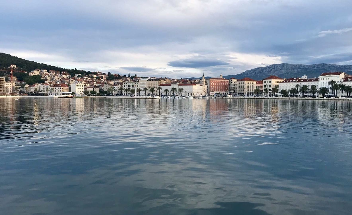 Vue du littoral depuis la mer, reflétant le paysage urbain et les montagnes.