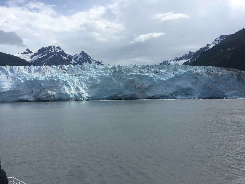 Un glacier avec un arrière-plan de montagnes et un ciel nuageux.
