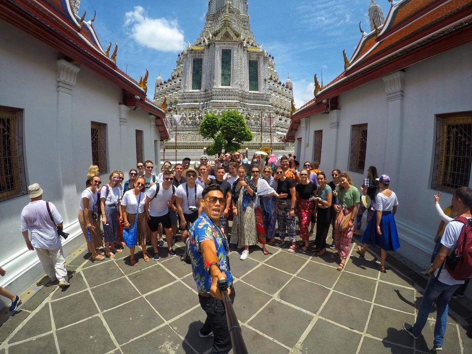 A large group taking a selfie in front of an ornate temple.