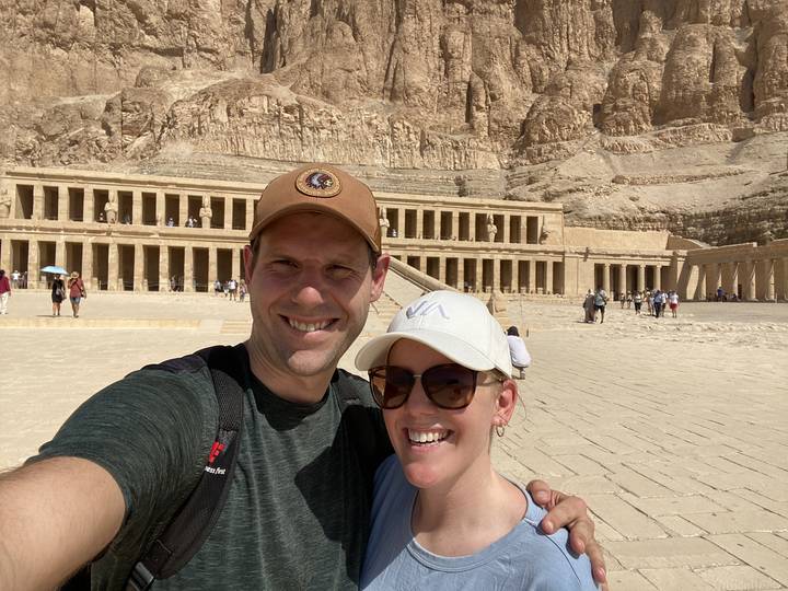 Selfie à l'envers d'un couple avec des ruines antiques en arrière-plan.
