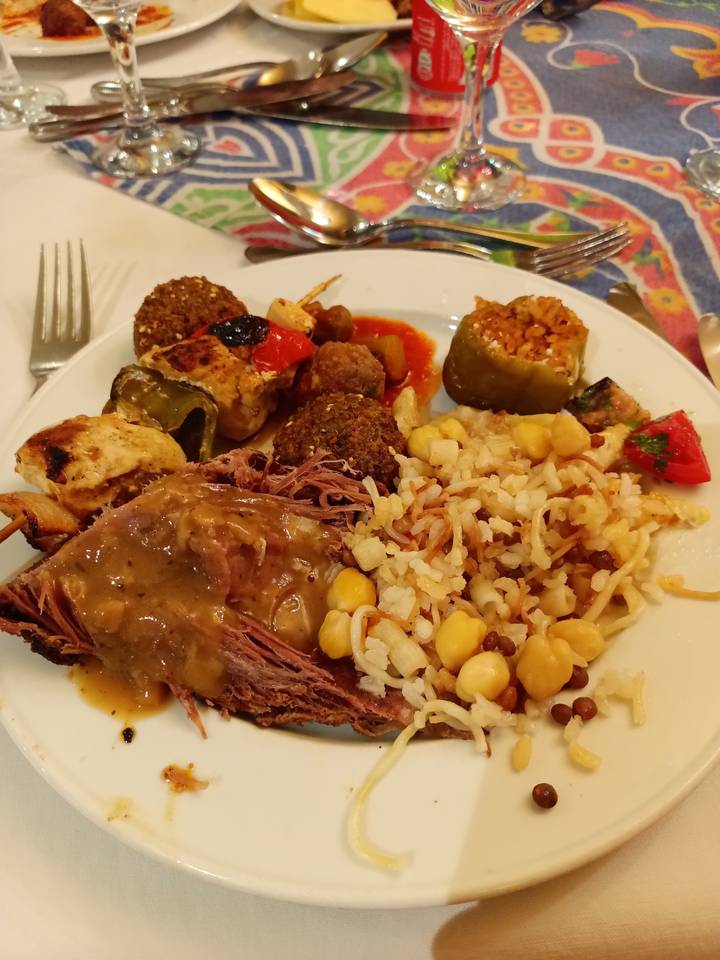 Une assiette contenant du riz, des pois chiches, des légumes et de la viande.