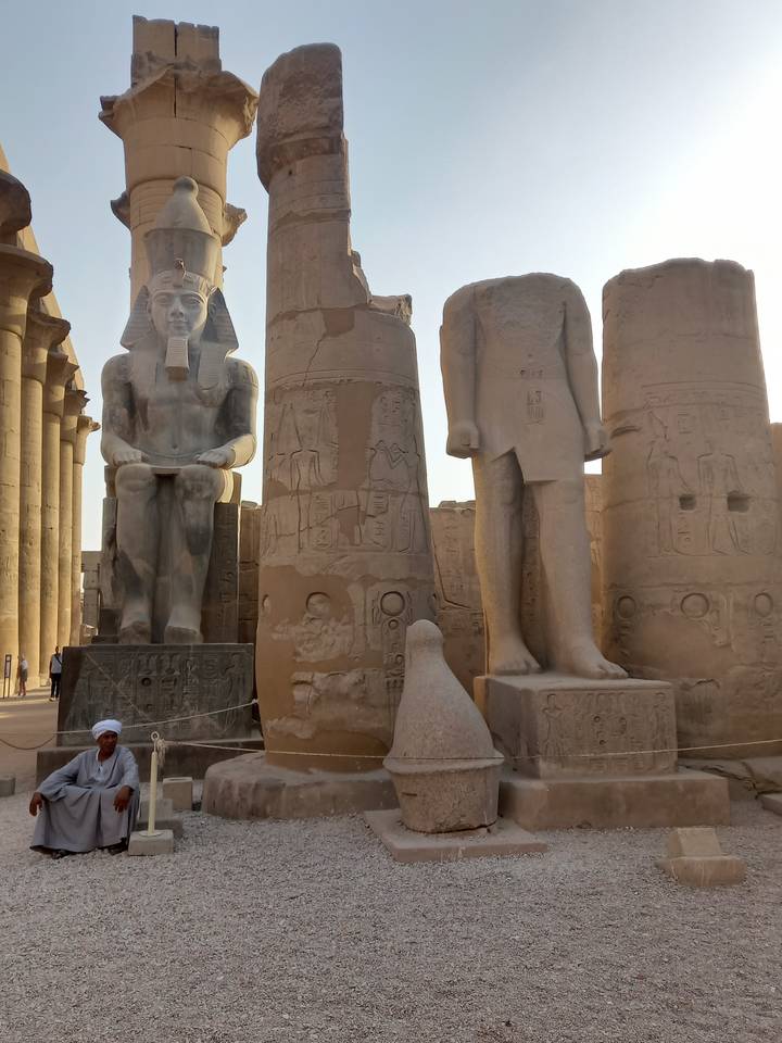 Statues et ruines de l'Égypte antique dans un cadre ouvert.
