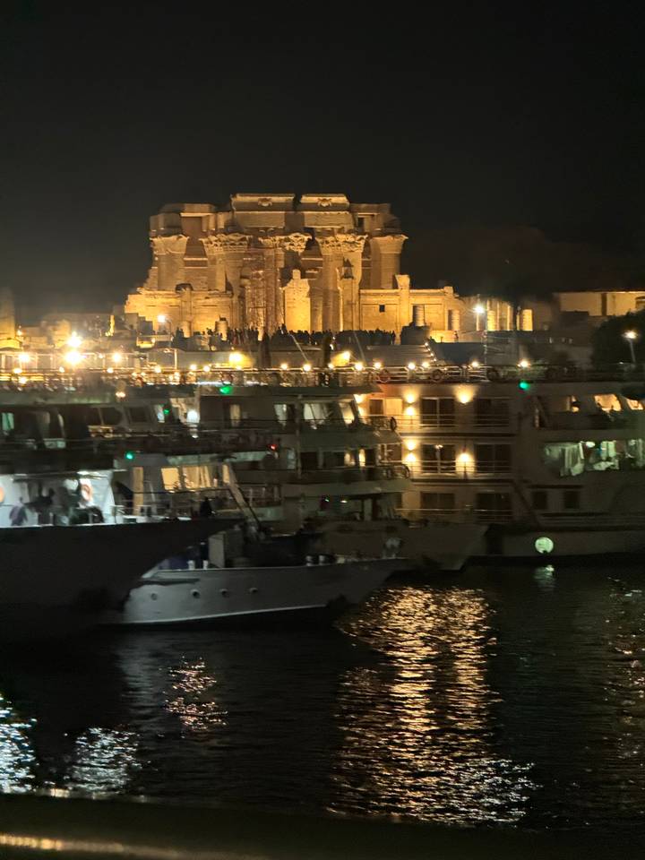 Vue nocturne d'une ville avec les lumières se reflétant sur l'eau.
