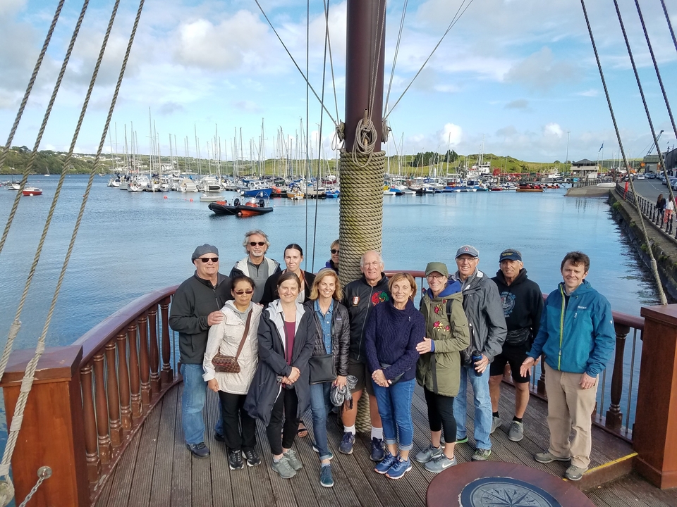 Groupe posant sur un bateau avec vue sur une marina et un ciel dégagé.