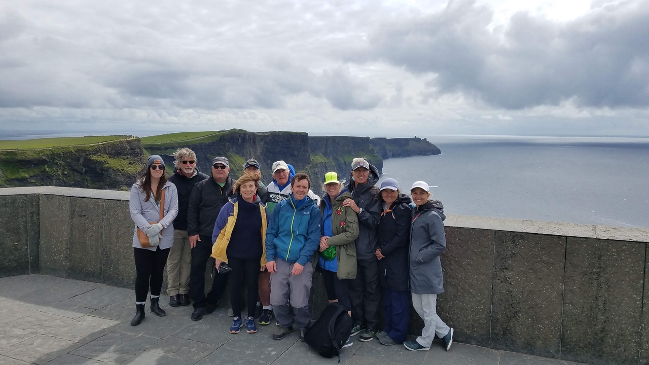 Groupe de touristes posant devant des falaises emblématiques au bord de la mer.