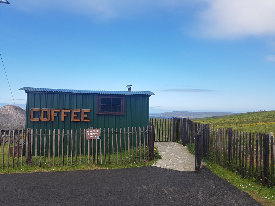 Une petite cabane verte au bord de la mer avec une enseigne CAFÉ.