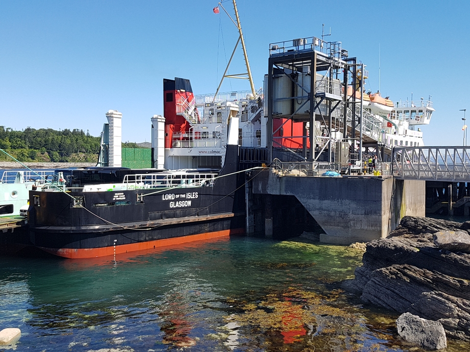 Traversier amarré à un quai avec une eau claire en dessous.
