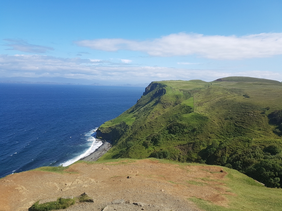 Falaise avec de l'herbe verte et un océan bleu.