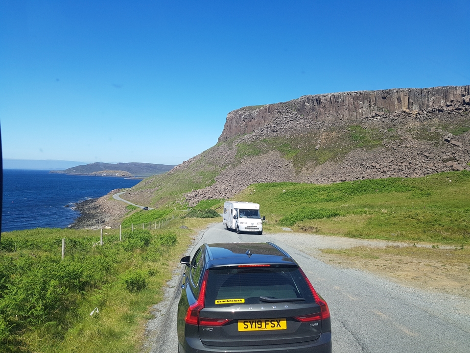 Route côtière avec des voitures roulant le long de falaises et de l'océan.