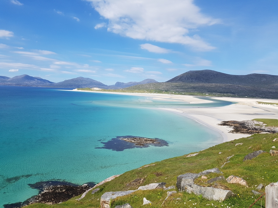 Vue panoramique d'une plage immaculée aux eaux bleu-vert.
