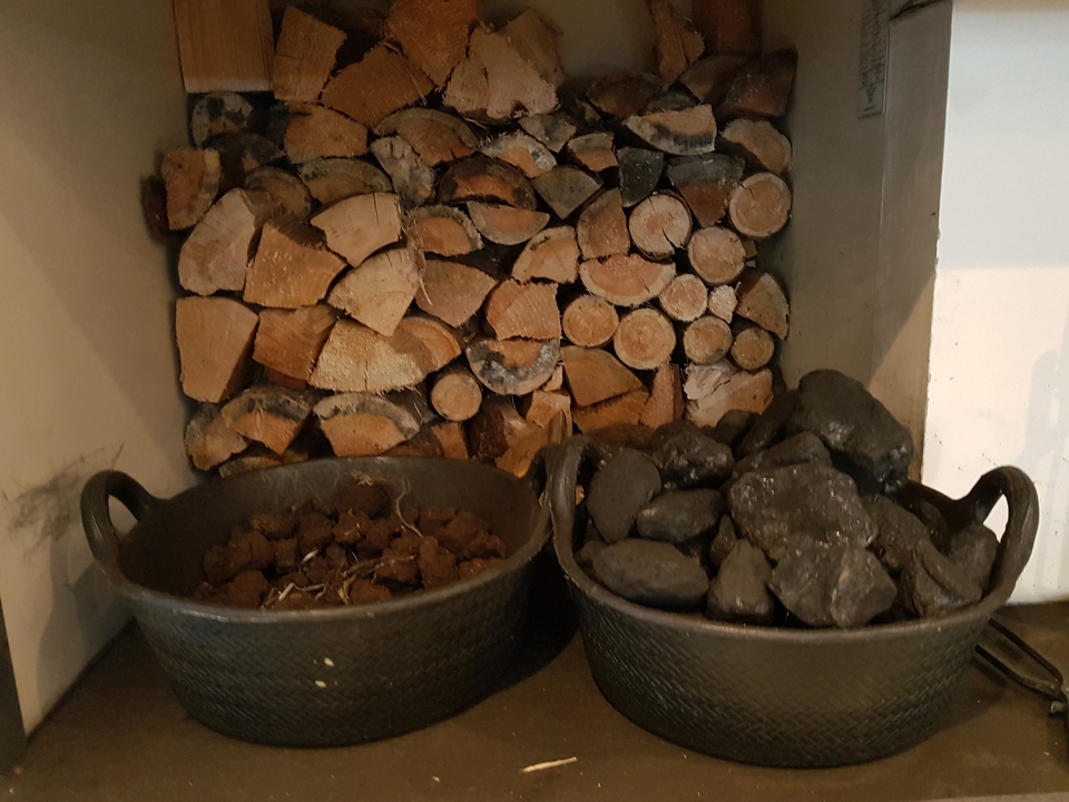 Bois de chauffage et charbon stockés dans des paniers près d'un mur.