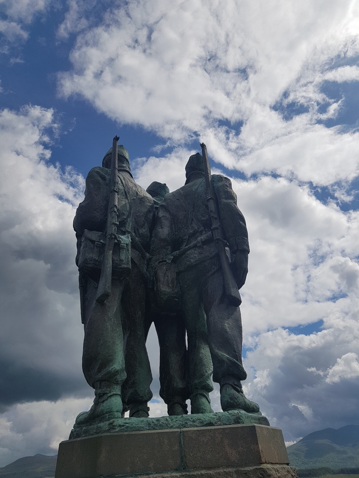Trois statues de soldats regardant au loin sous un ciel dégagé.