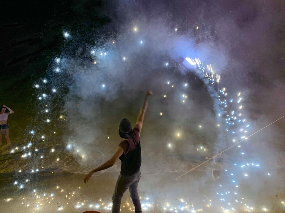 Personne crée un spectacle enflammé sur la plage la nuit.