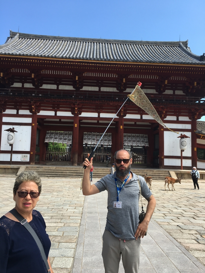 Des touristes debout devant la façade d'un temple traditionnel.