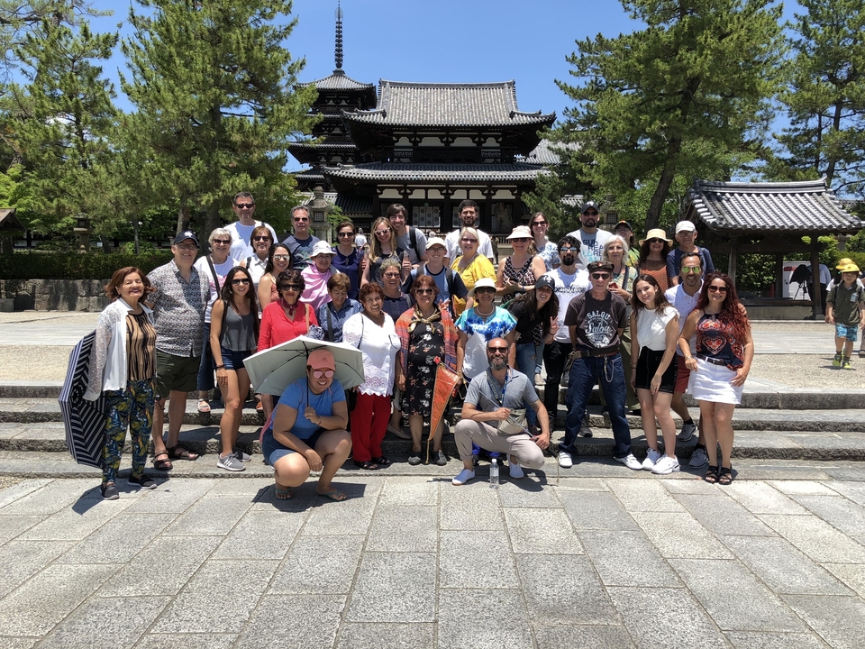 Grand groupe de touristes posant devant un temple traditionnel.