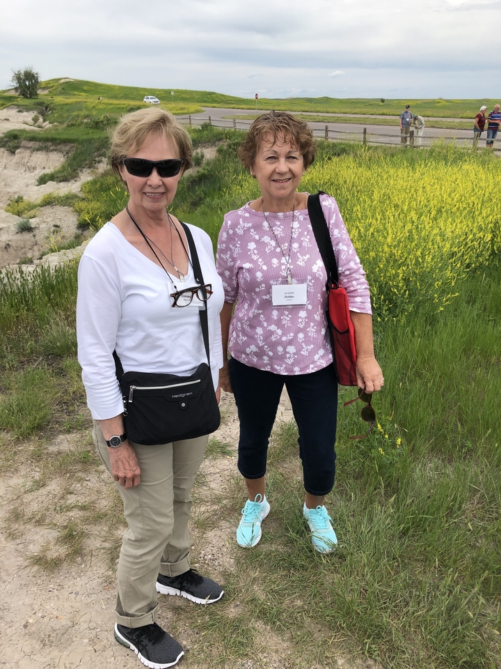 Deux femmes debout sur un sentier avec des fleurs sauvages.