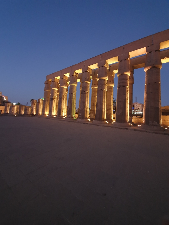Vue nocturne de colonnes antiques illuminées.