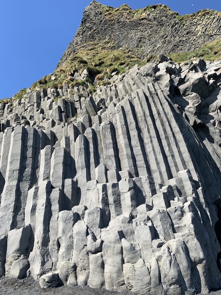 Basalt columns forming a geological feature under the blue sky.