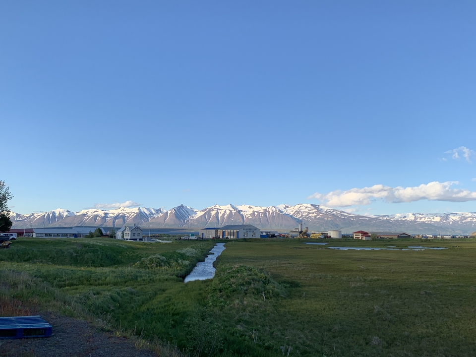 Rural landscape with snowy mountains and clear blue sky.