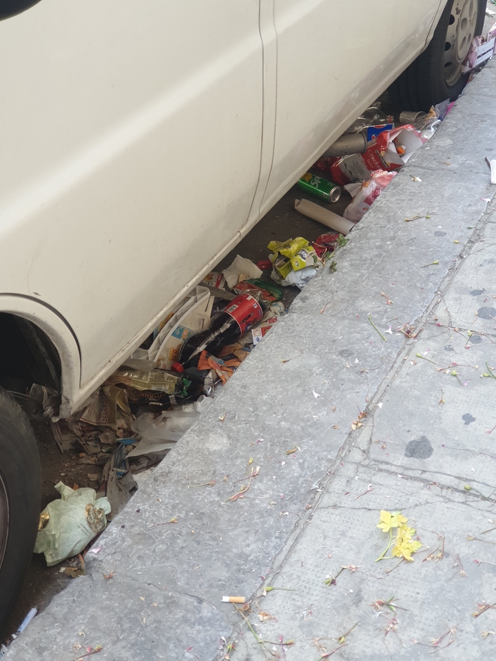 Détritus et déchets sous un véhicule garé dans une rue de la ville.