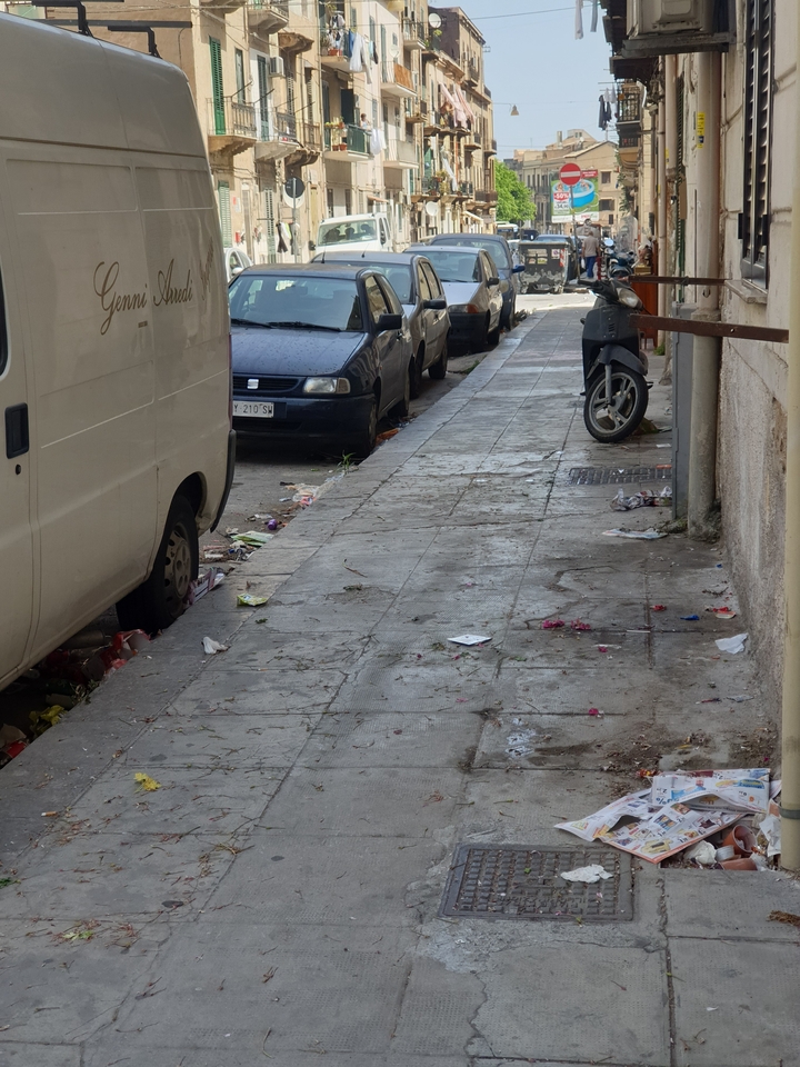 Trottoir sale avec des véhicules garés le long de la rue.