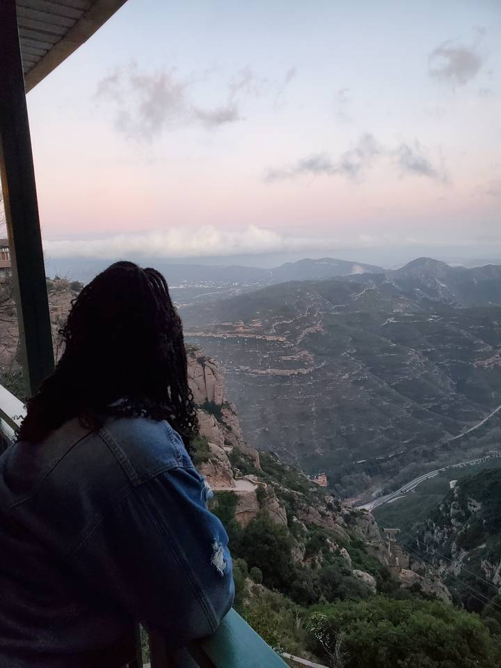 Vue panoramique d'une personne contemplant un paysage montagneux.
