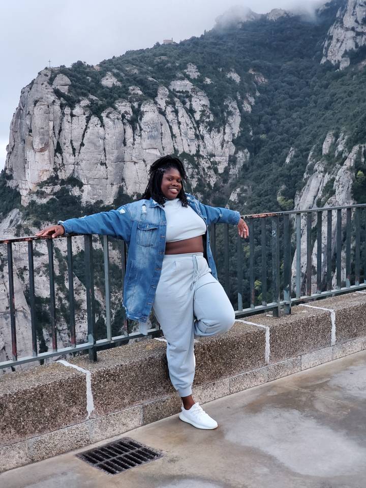 Personne appuyée sur une rambarde avec des falaises rocheuses en arrière-plan.