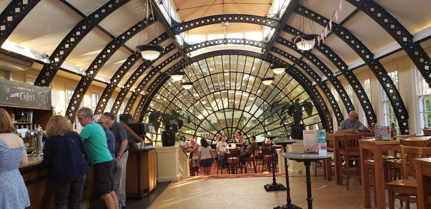 Intérieur de café avec une grande fenêtre voûtée et des clients.