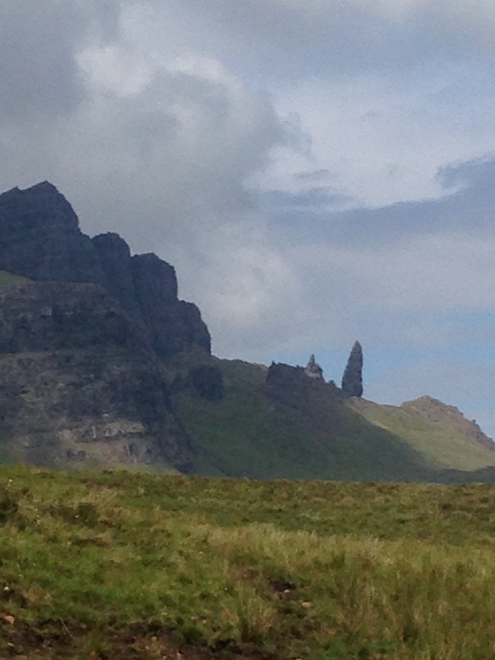 Vue lointaine de pics montagneux escarpés sous un ciel nuageux.