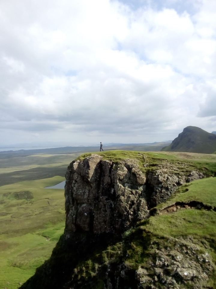 Personne debout au bord d'une falaise rocheuse avec une vue panoramique.