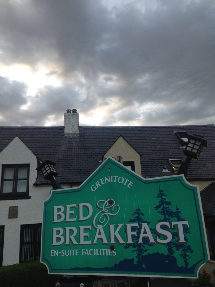 Un panneau avec un arrière-plan vert contre un bâtiment avec une cheminée.