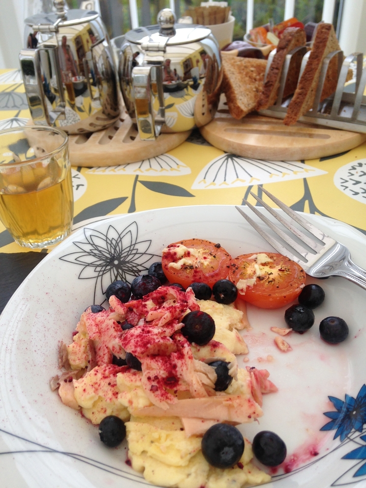 Une assiette de nourriture avec des tomates, des myrtilles, et une boisson à côté.