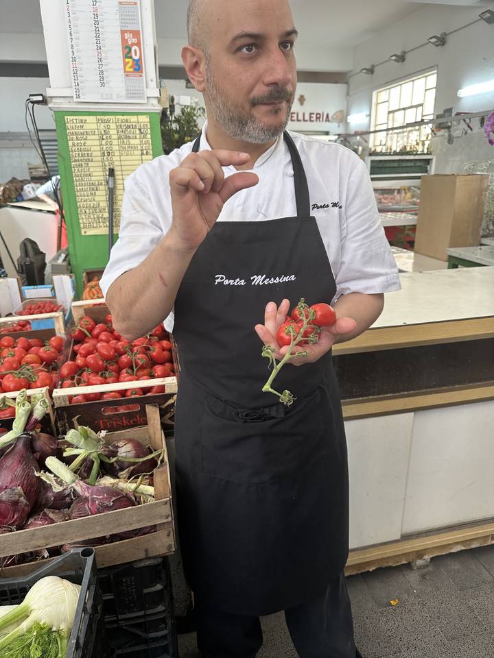 Vendeur tenant des tomates fraîches dans un marché.