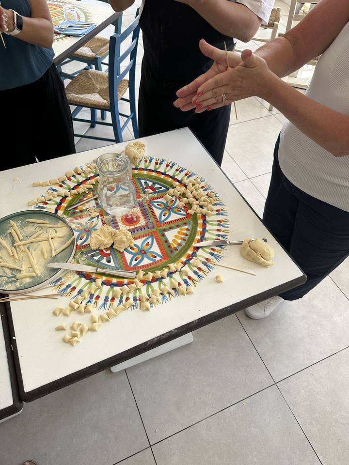 Des mains pétrissant de la pâte à pâtes sur une table décorative colorée.