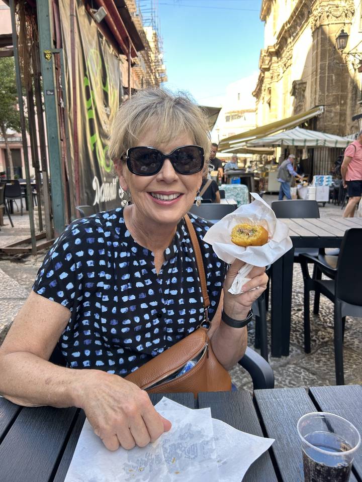 Personne avec une pâtisserie souriante dans un café en bordure de rue.