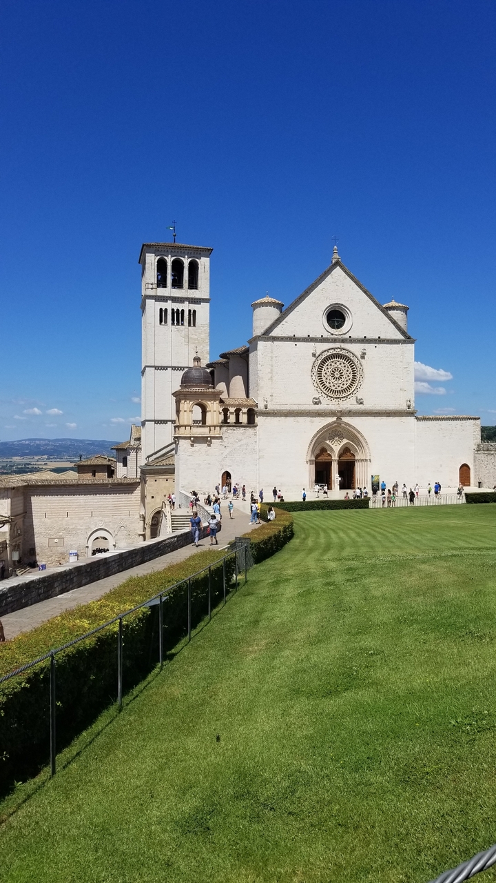 Une grande basilique avec des gens qui se promènent dans les espaces verts.