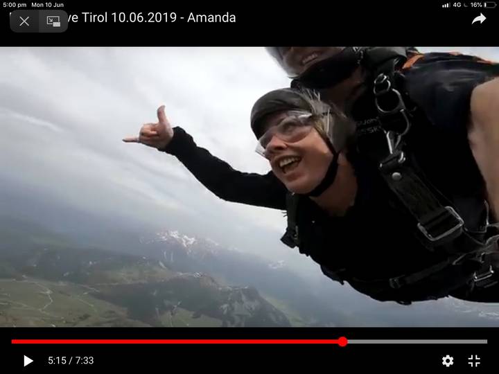 Two people skydiving with a view of mountains below.