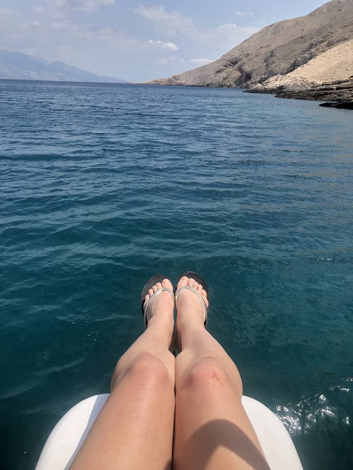 Feet in sandals over a view of the sea.