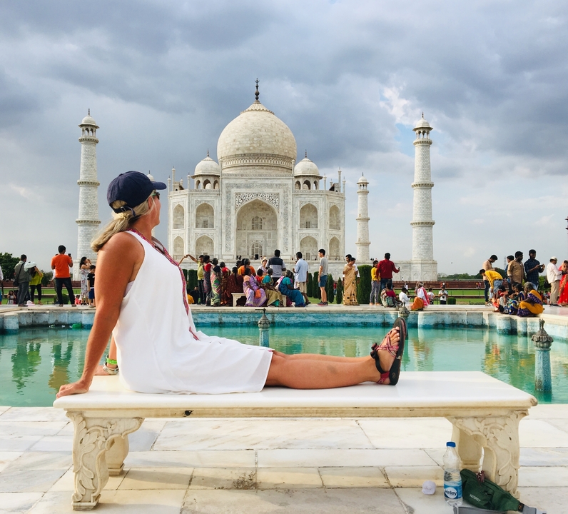 Femme posant devant le Taj Mahal avec une foule en arrière-plan.