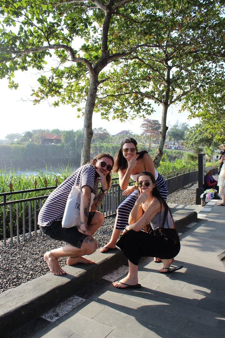 Three friends posing casually near a scenic view.