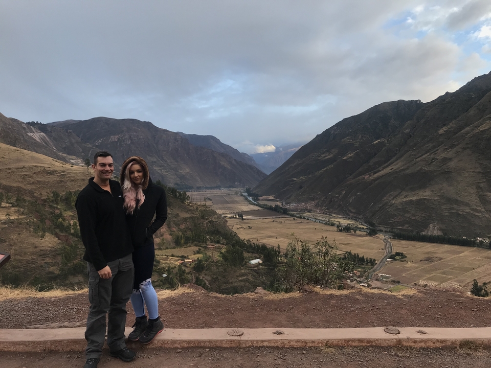 Couple posant devant un paysage de vallée époustouflant avec des montagnes.