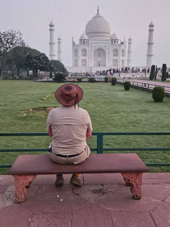 Une personne assise sur un banc regardant le Taj Mahal